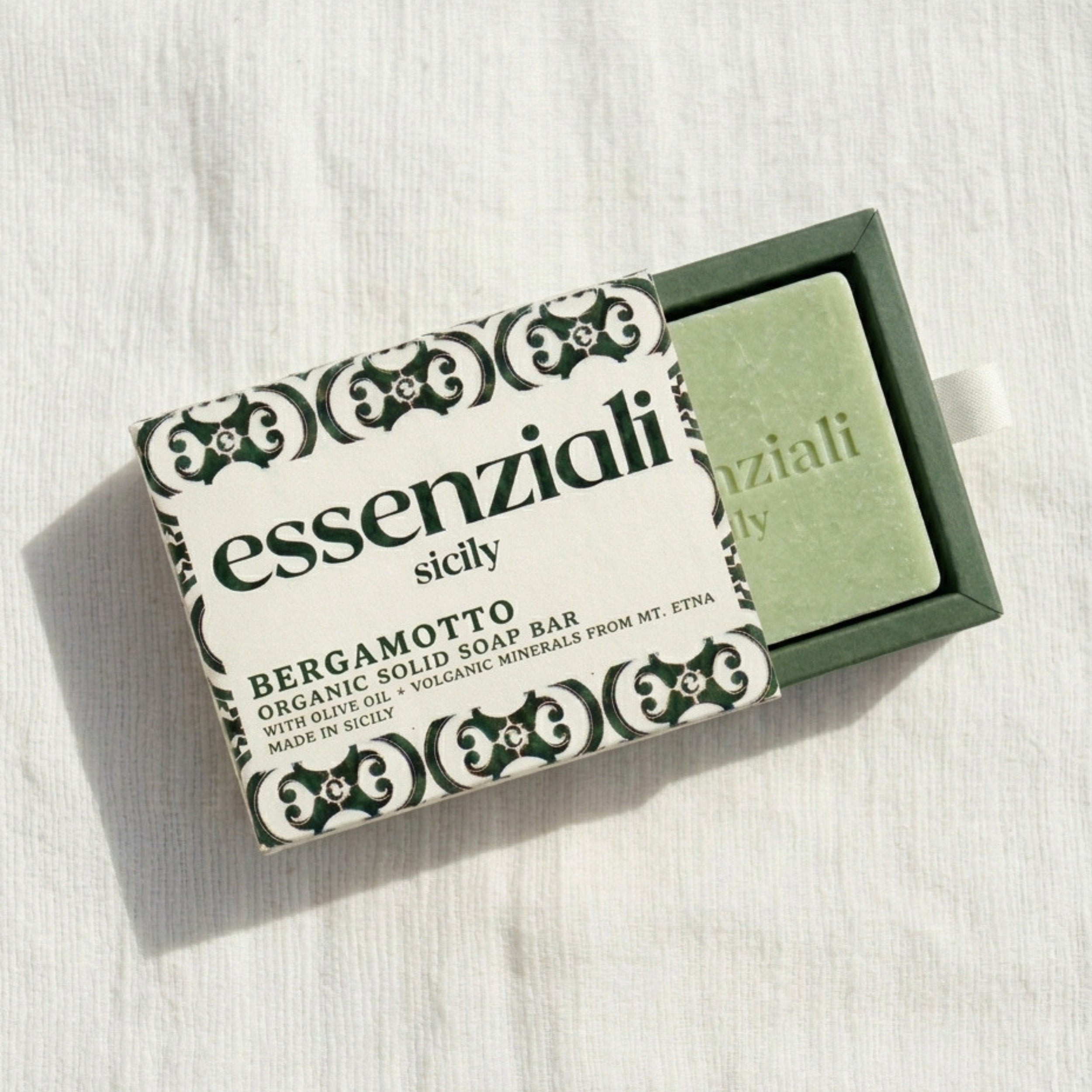 Green soap bar with 'essenziali sicily' packaging on a white background