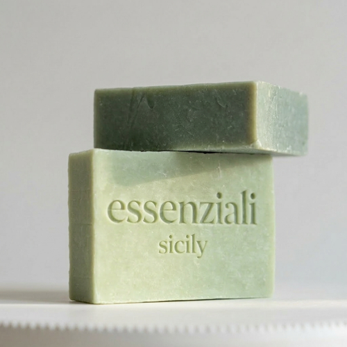 Green bar of soap with 'essenziali sicily' branding on a light gray background