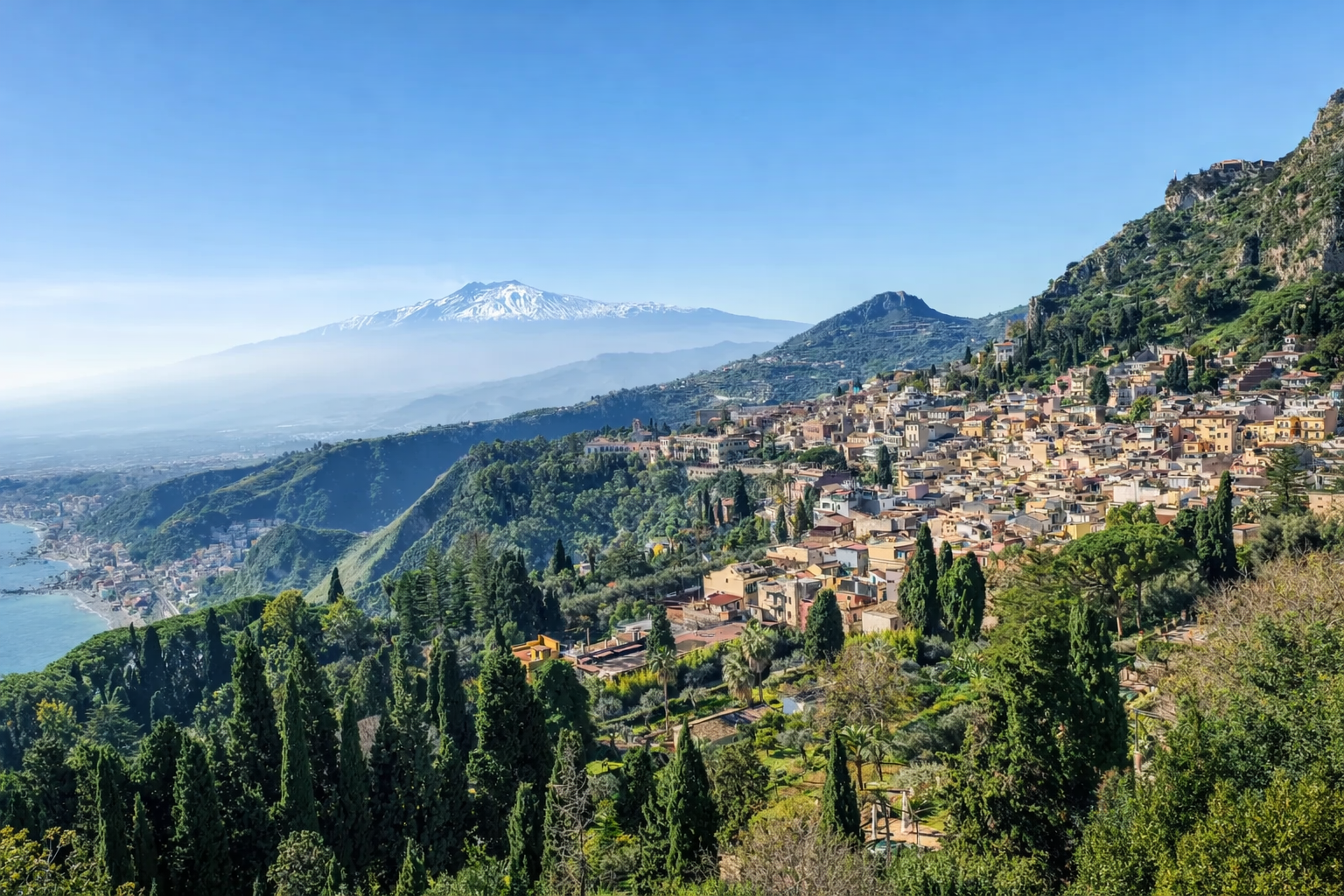 Hilly Sicilian landscape with a town and Mount Etna in the background